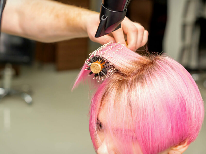 drying-short-pink-hair-young-caucasian-woman-with-black-hairdryer-black-round-brush-by-hands-male-hairdresser-hair-salon-close-up